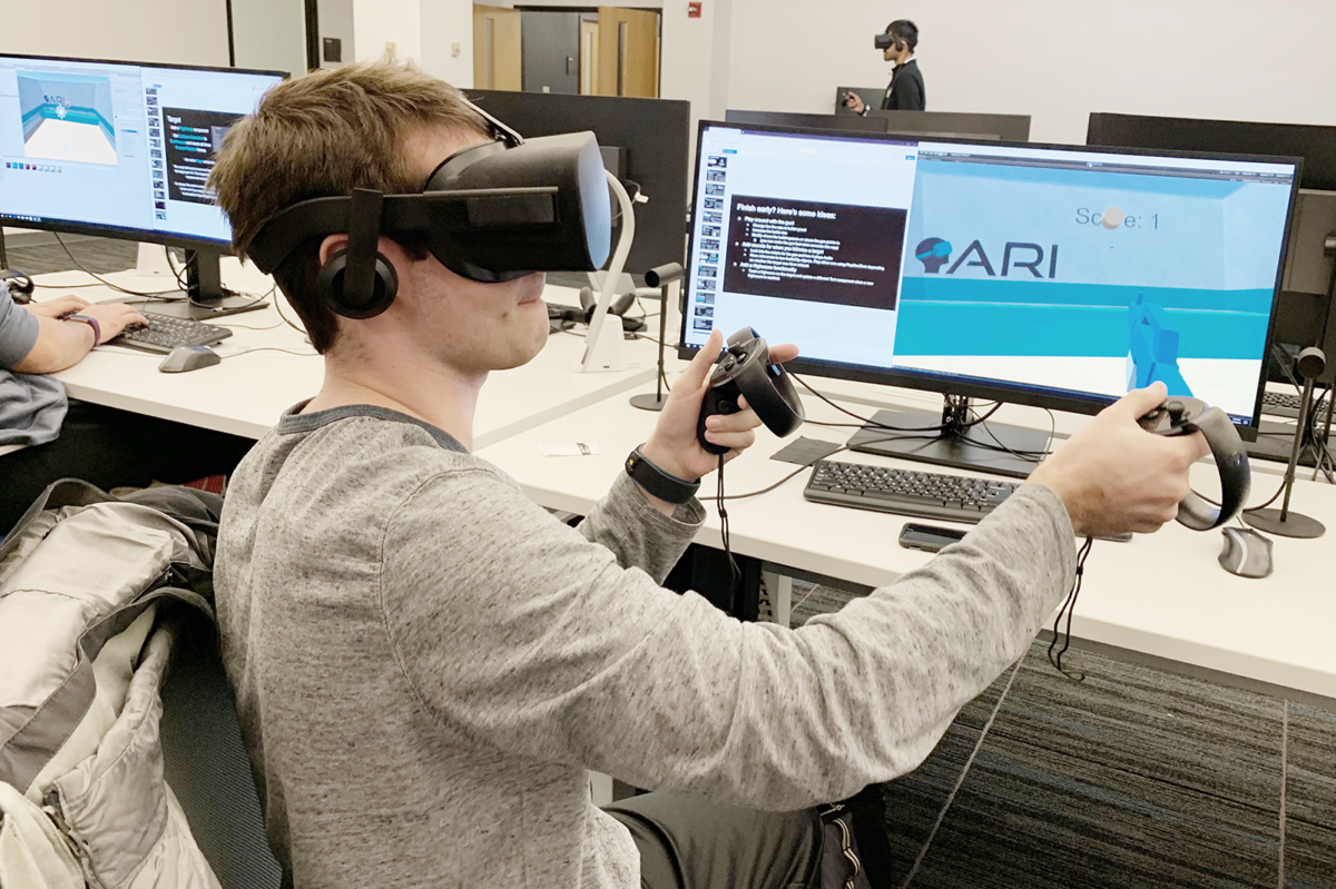 Student testing 3D virtual reality environment using VR headset and hand controllers