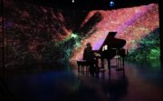 Students playing piano in front of big screen showing the Milky Way Galaxy