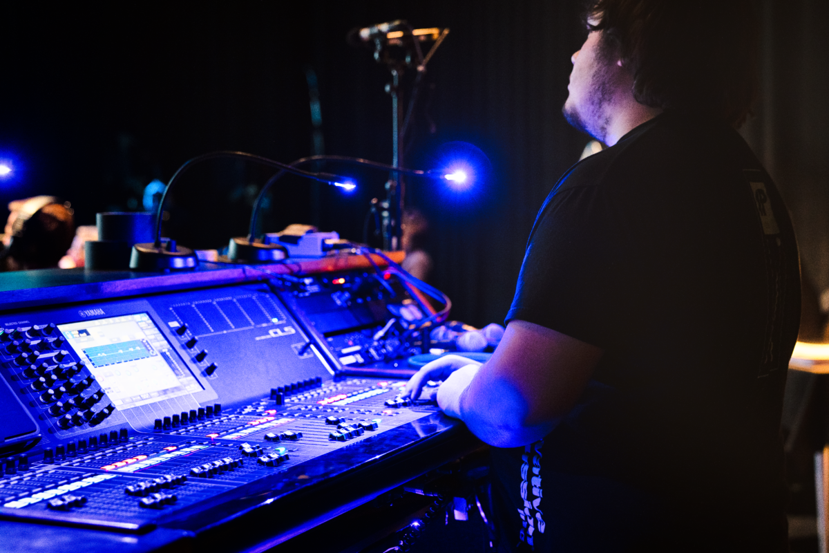 A student consultant assist with audio controls during a production in the Video Studio