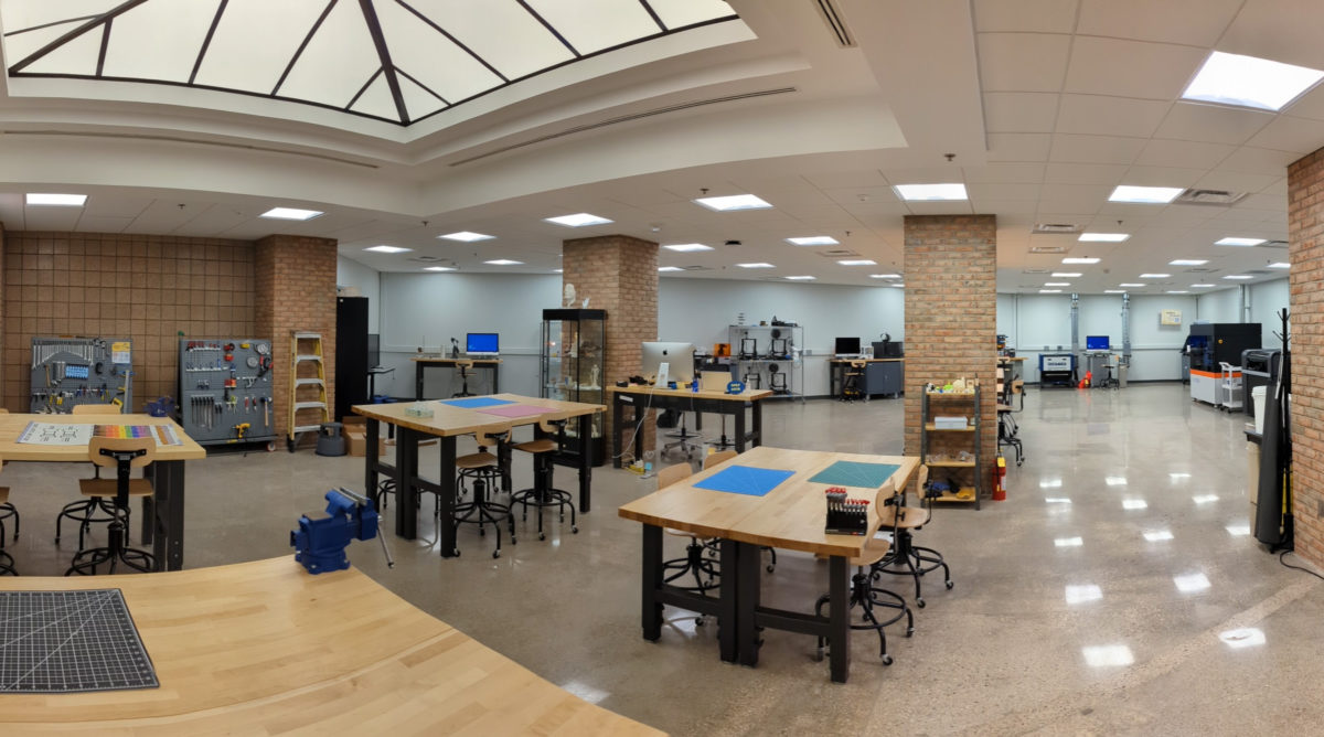 A panoramic perspective showing the interior of the new Fabrication Underground facility showing worktables in the foreground and multiple 3D printers and electronics workbenches in the background