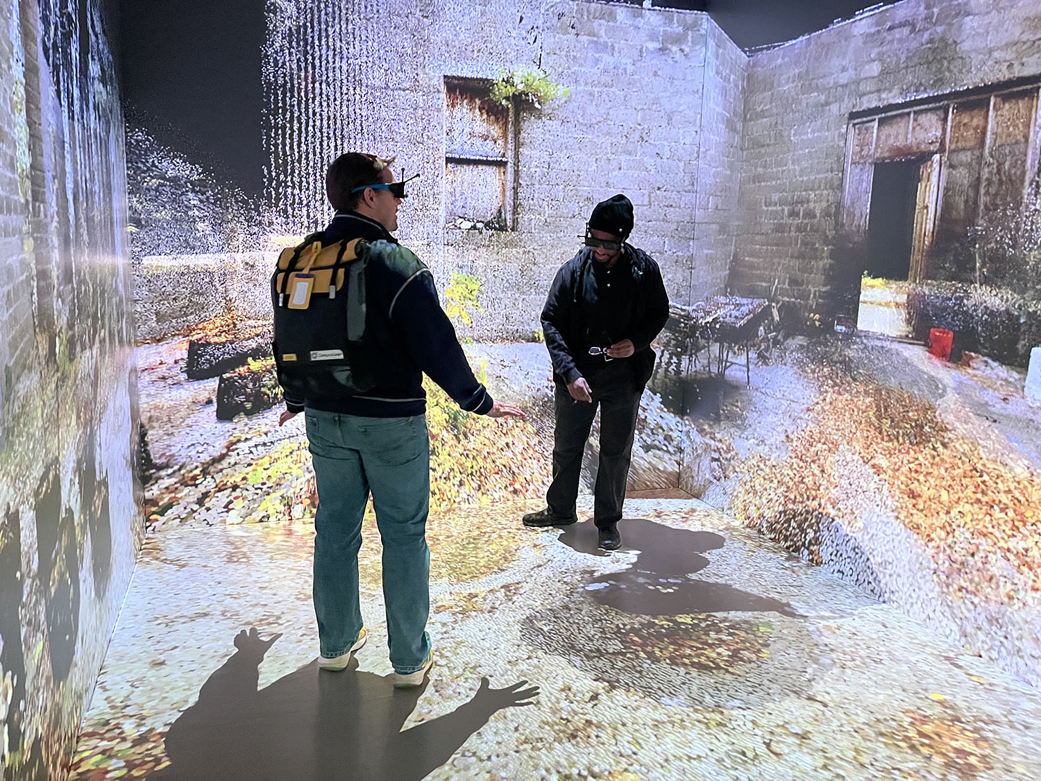 Photo of 2 people inside the MIDEN immersive VR space in the Duderstadt Center.