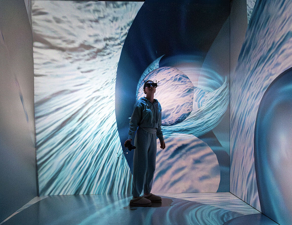 Person standing in the MIDEN VR immersive environment with images of water on the walls & floor.