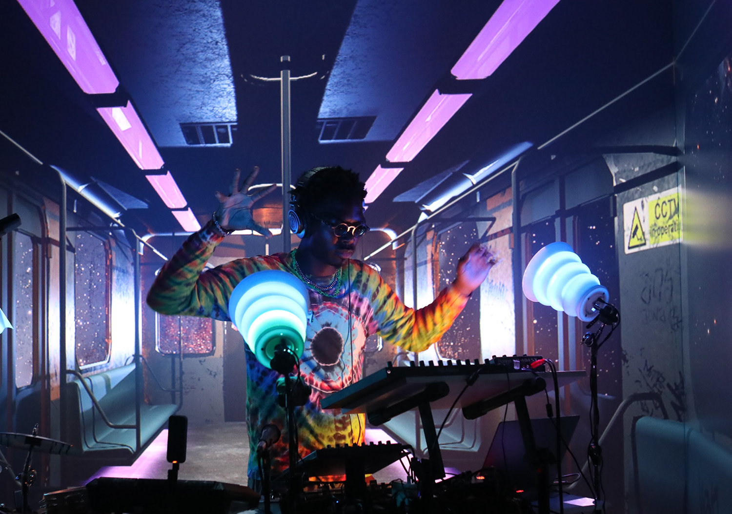 Photo of a drummer performing in a virtual space with purple and blue lighting.