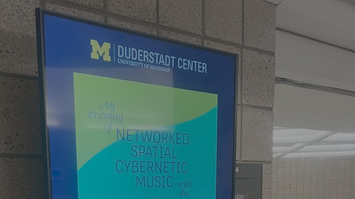 Image of a digital sign outside design lab 2 that is displaying weather, the time, the Duderstadt Center logo, and an advertisement for a summer music technology camp.