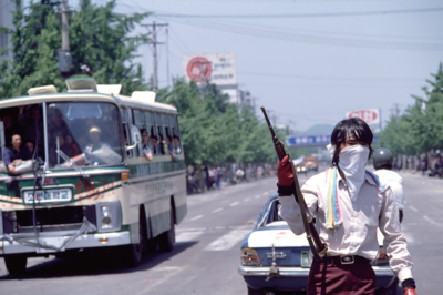 Protestor with gun and scarf covering their face.