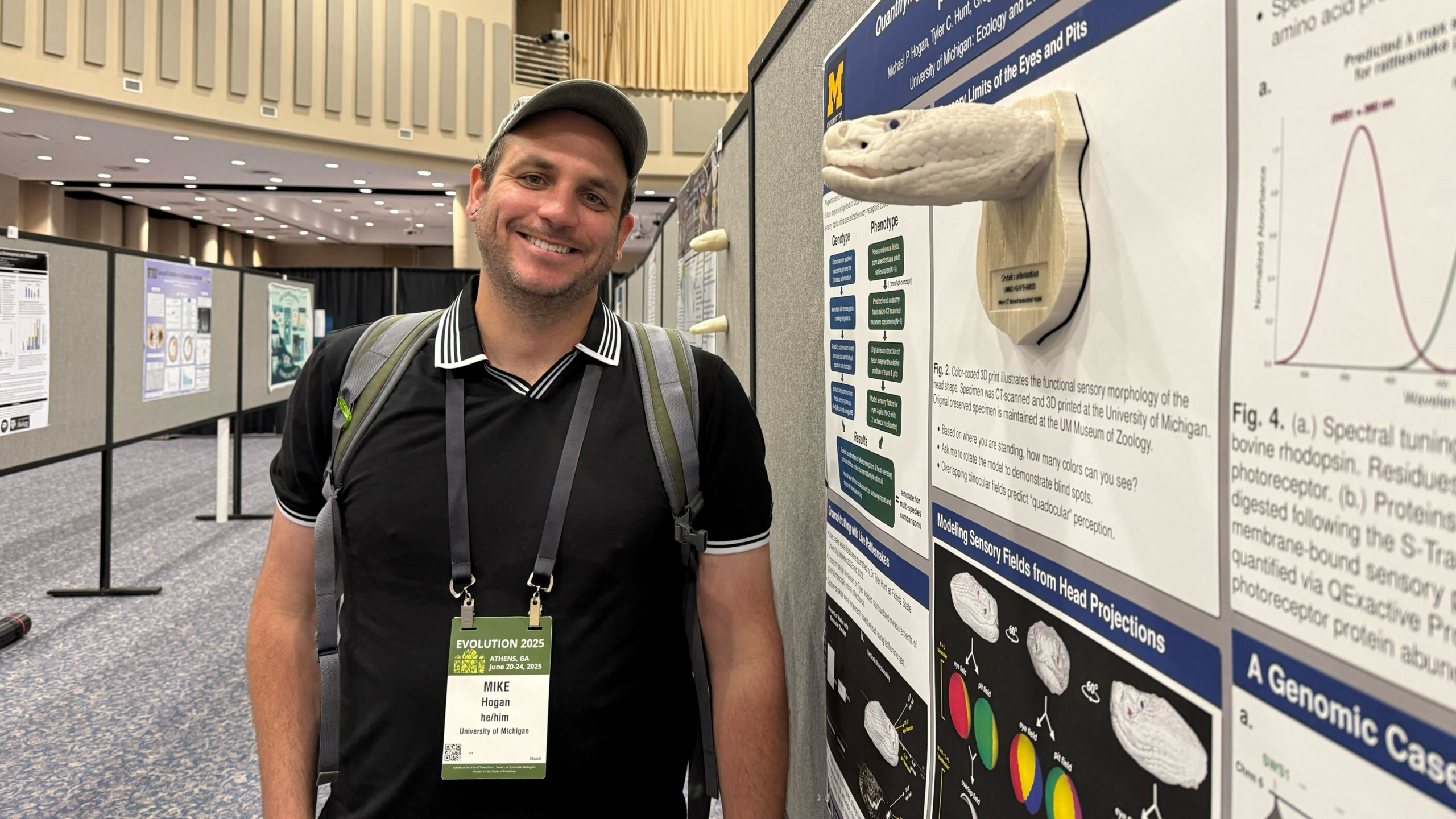 Mike Hogan poses with his poster and a 3D printed snake, an Eastern diamondback rattlesnake, at a conference.